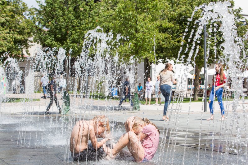 Ein Junge und ein Mädchen beim Wasserspiel auf dem Kirchplatz